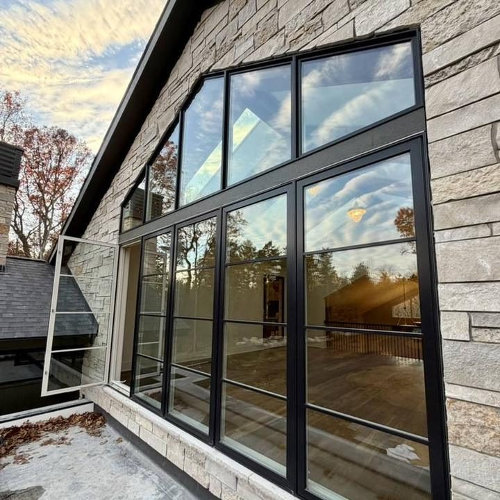 Large black-framed windows on a stone home after cleaning.