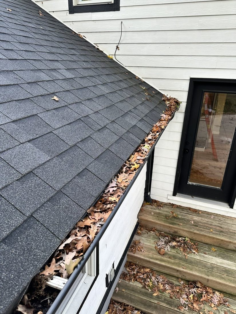 A gutter run packed solid with wet oak leaves.