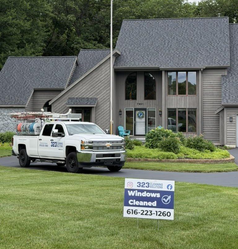 A 323 Cleaning Solutions truck on the drive and a Windows Cleaned yard sign on the lawn outside a customer's home.